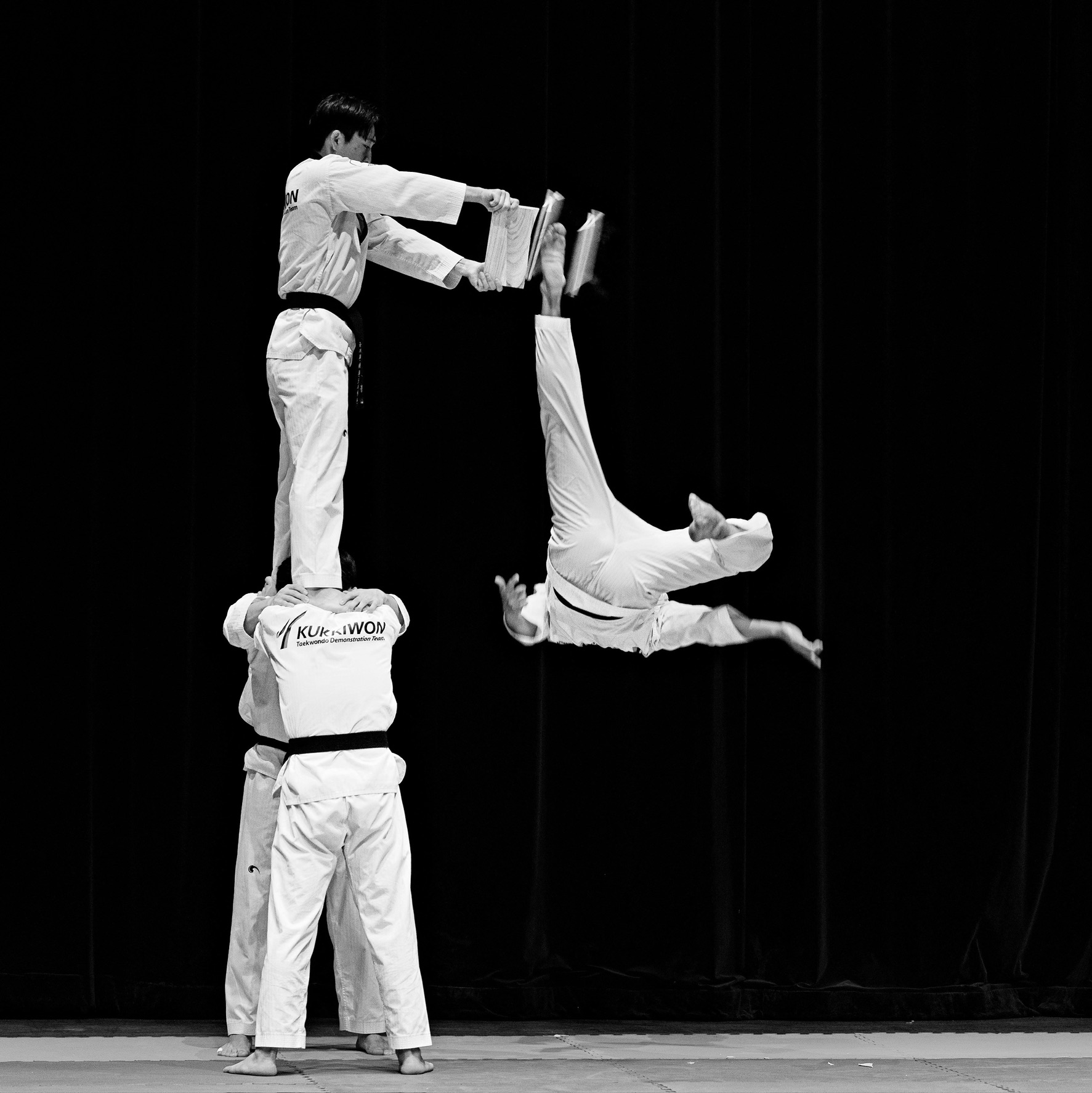 Taekwondo image in black and white. Man breaking board with his foot.